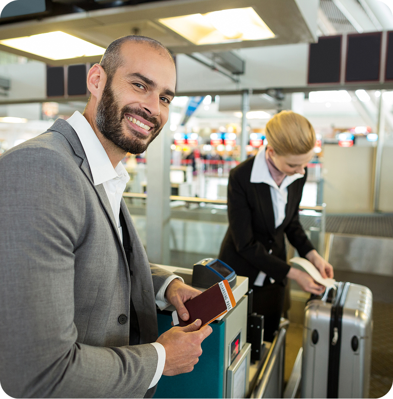 smiling-businessman-standing-with-passport-while-attendant-sticking-tag-luggage